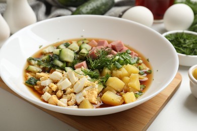 Photo of Delicious okroshka soup and ingredients on white table, closeup