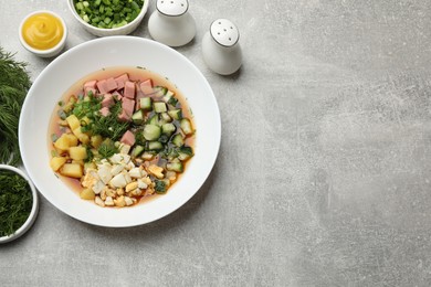 Photo of Delicious okroshka soup and ingredients on grey table, flat lay. Space for text