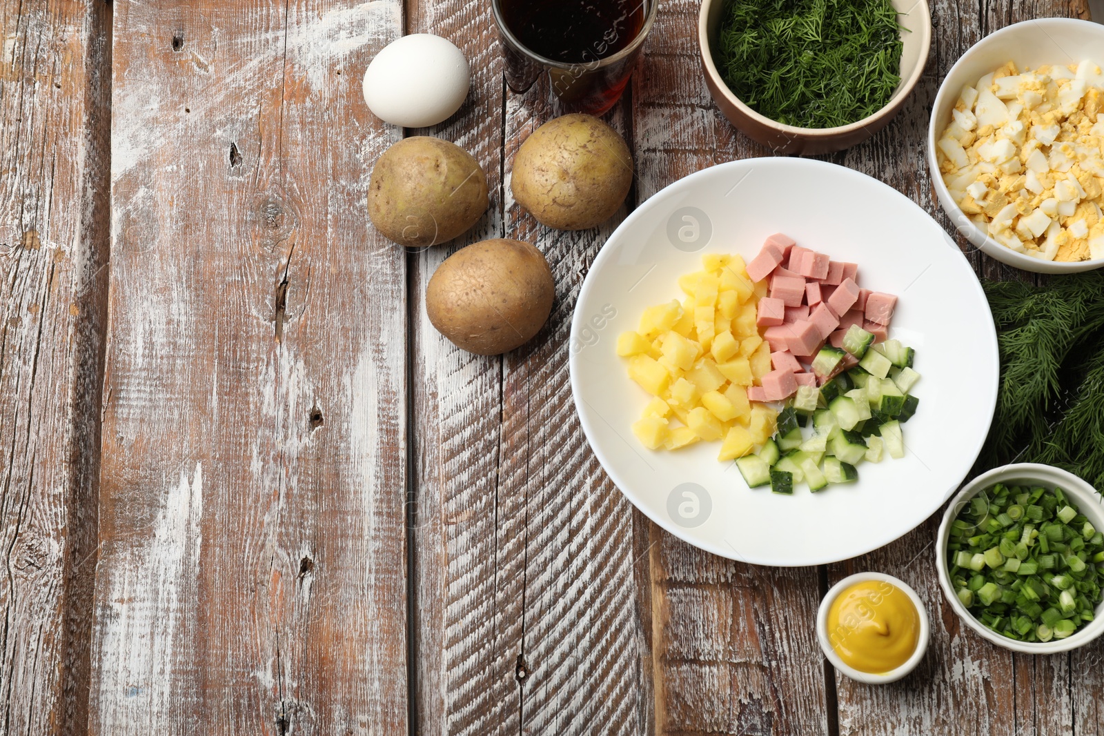 Photo of Different ingredients for okroshka soup on wooden table, flat lay. Space for text