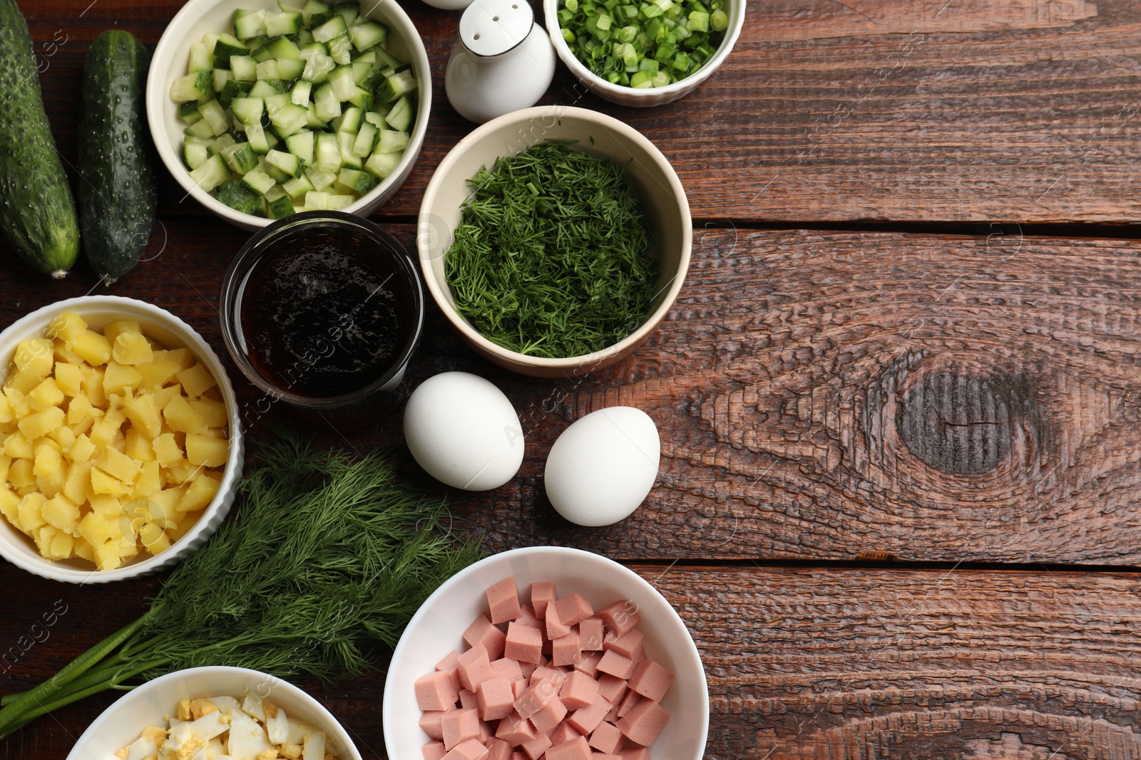 Photo of Different ingredients for okroshka soup on wooden table, flat lay. Space for text