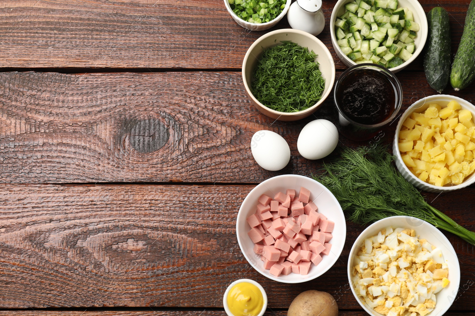 Photo of Different ingredients for okroshka soup on wooden table, flat lay. Space for text