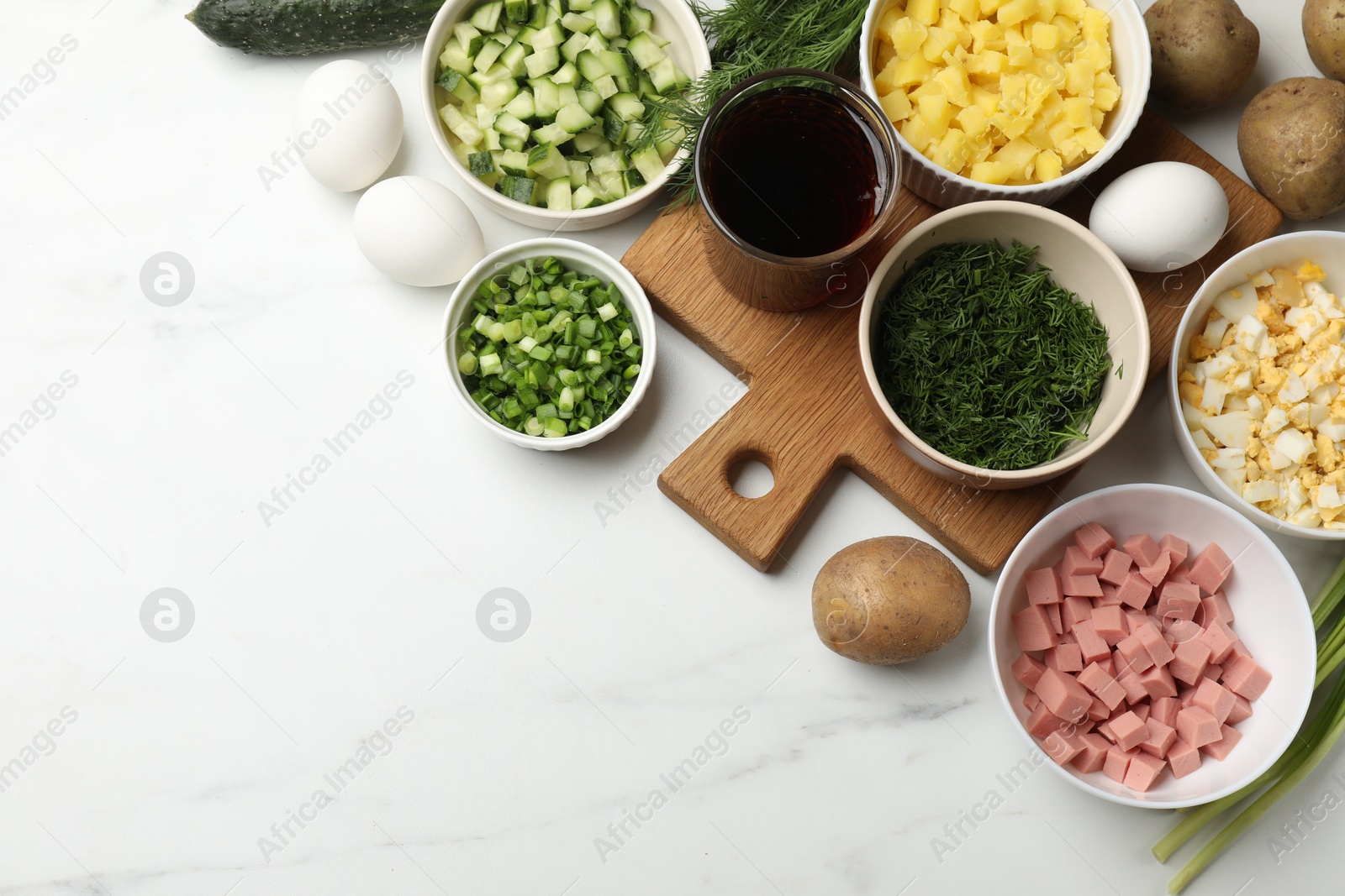 Photo of Different ingredients for okroshka soup on white table, flat lay. Space for text