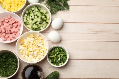 Photo of Different ingredients for okroshka soup on white wooden table, flat lay. Space for text