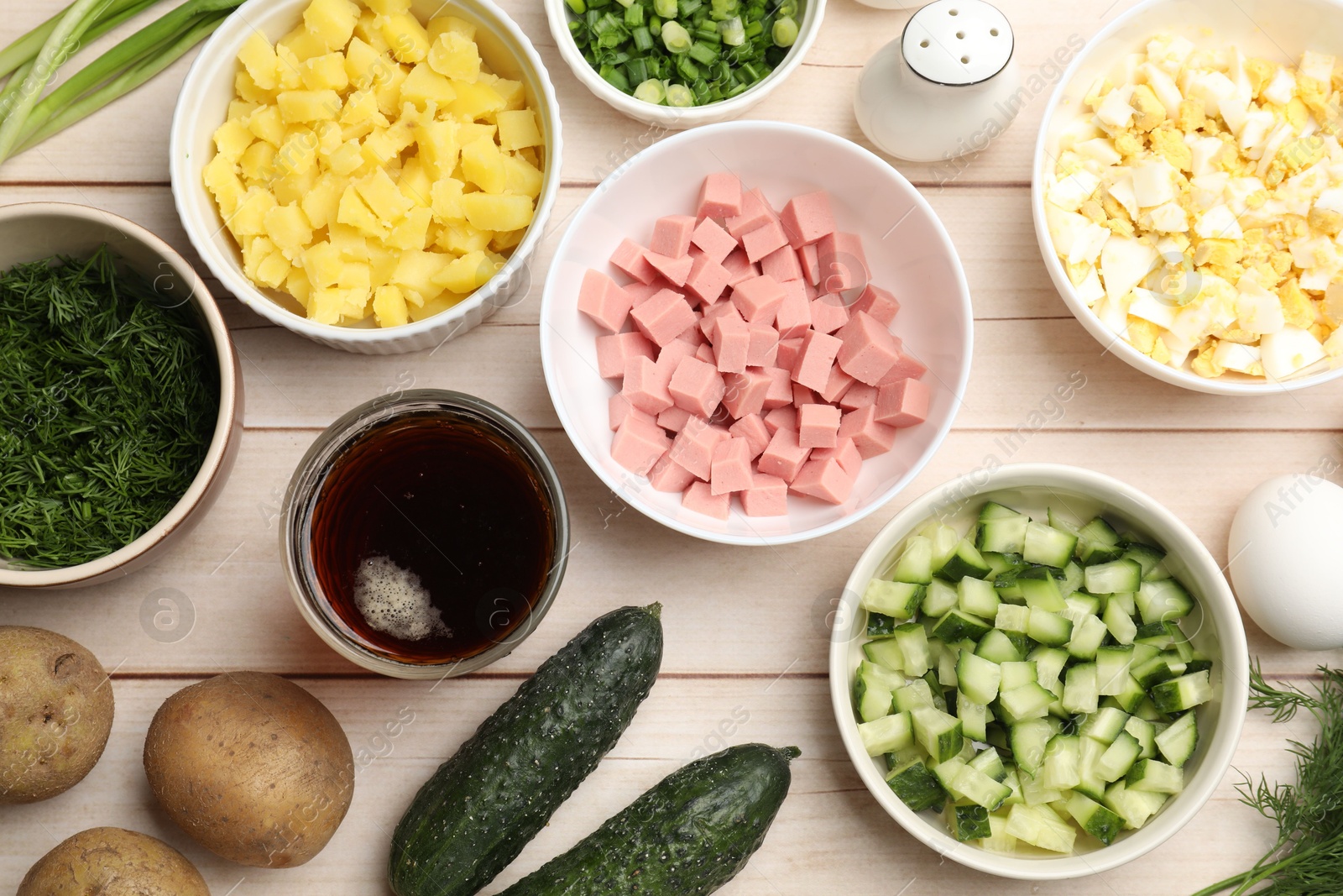 Photo of Different ingredients for okroshka soup on white wooden table, flat lay