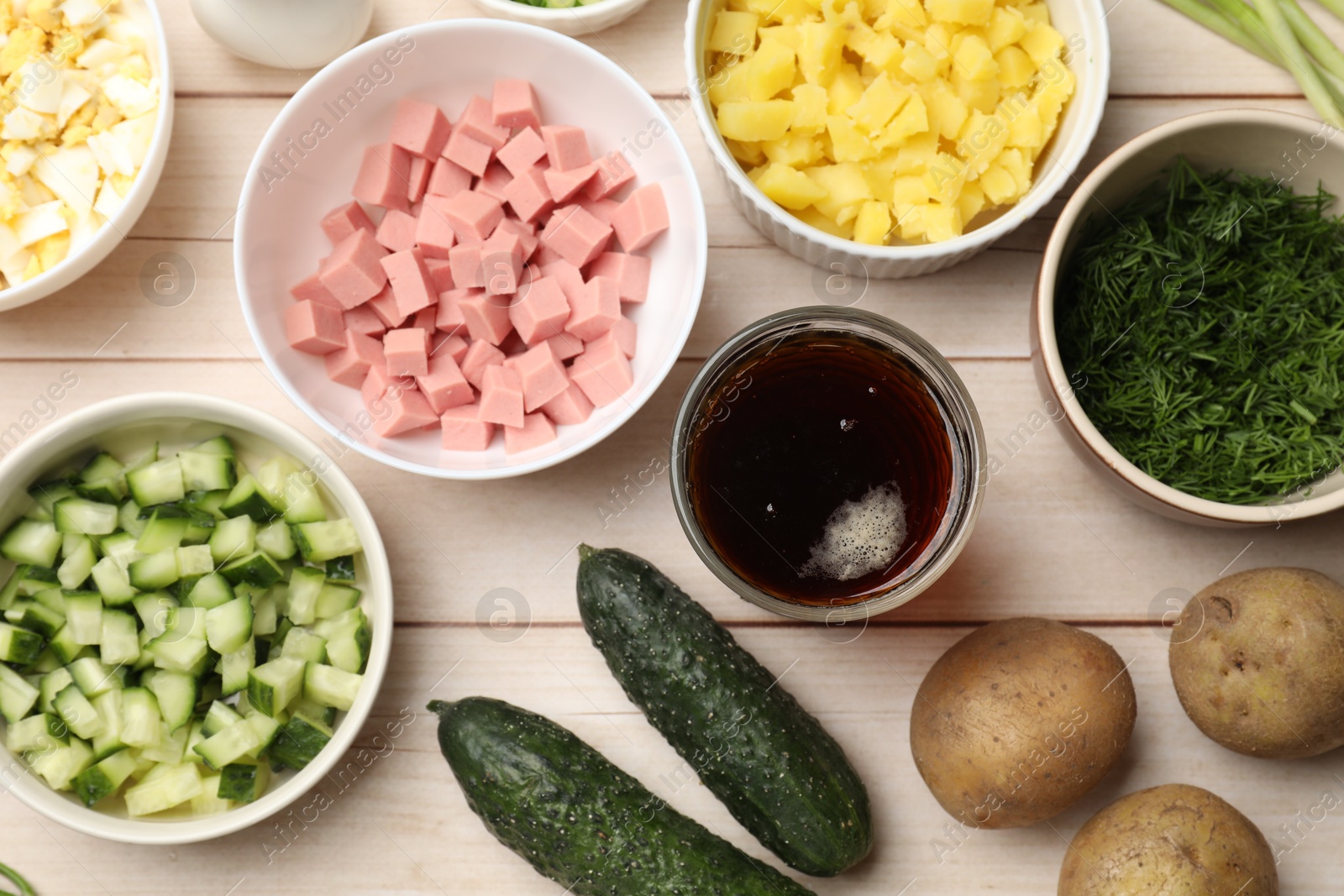 Photo of Different ingredients for okroshka soup on white wooden table, flat lay