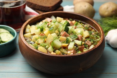 Photo of Delicious okroshka soup with kvass and ingredients on blue wooden table, closeup