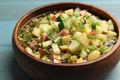 Photo of Delicious okroshka soup with kvass on blue wooden table, closeup