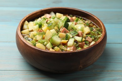 Photo of Delicious okroshka soup with kvass on blue wooden table, closeup