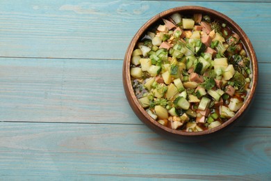 Photo of Delicious okroshka soup with kvass on blue wooden table, top view. Space for text