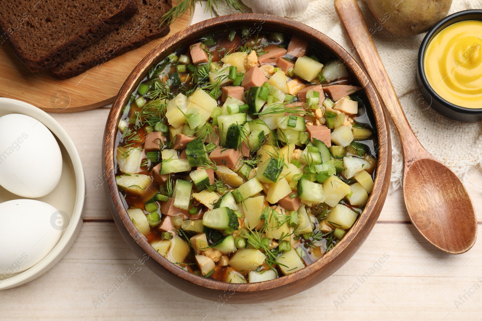 Photo of Delicious okroshka soup with kvass and ingredients on white wooden table, flat lay