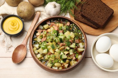 Photo of Delicious okroshka soup with kvass and ingredients on white wooden table, flat lay