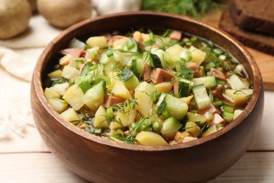 Photo of Delicious okroshka soup with kvass and ingredients on white wooden table, closeup