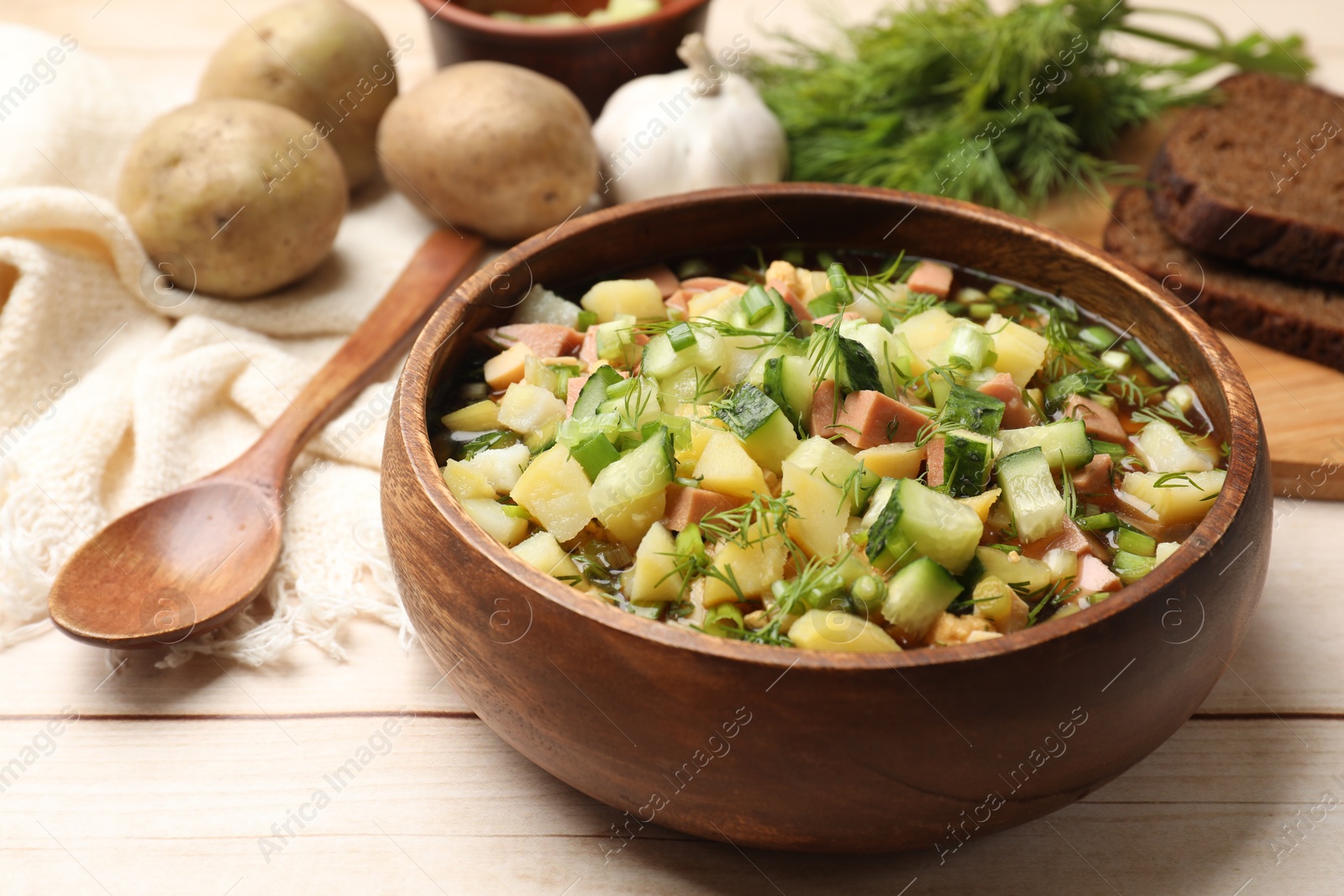 Photo of Delicious okroshka soup with kvass and ingredients on white wooden table, closeup