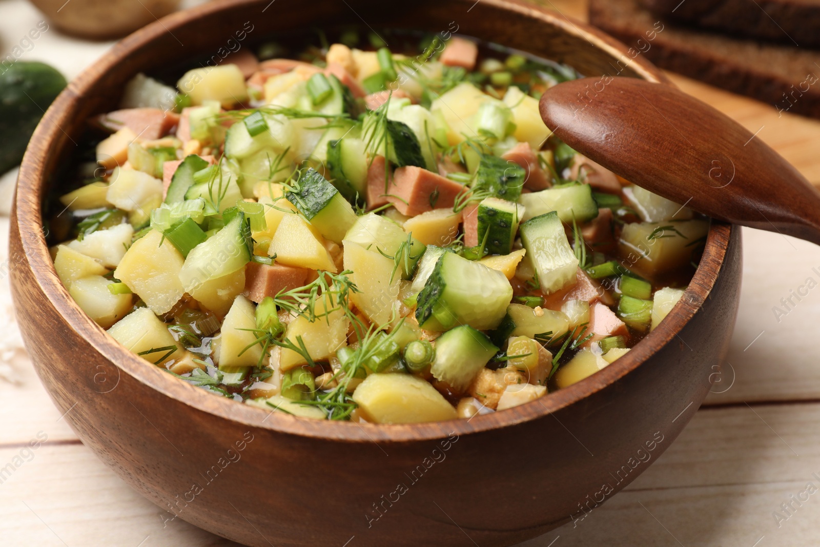 Photo of Delicious okroshka soup with kvass and ingredients on white wooden table, closeup