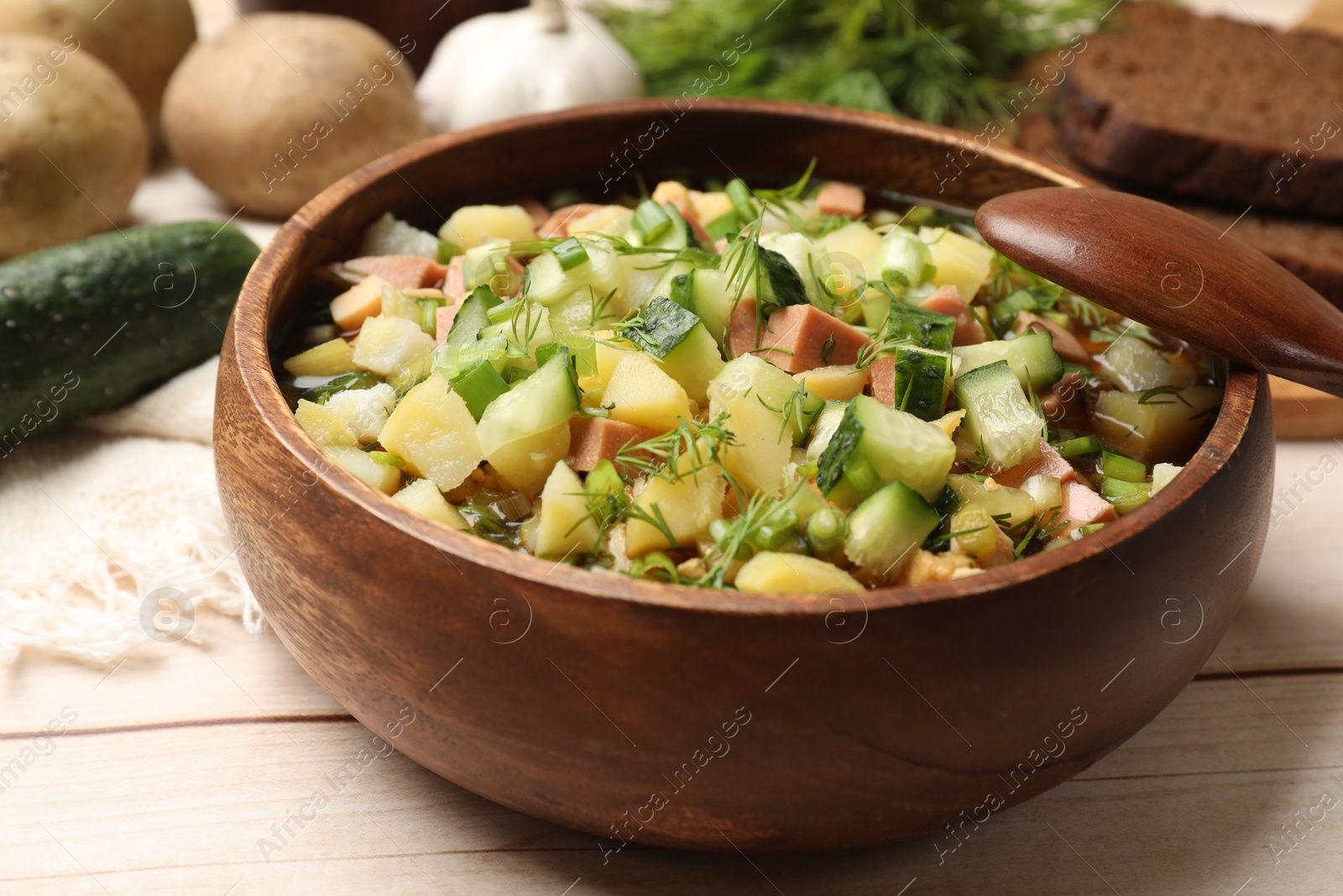 Photo of Delicious okroshka soup with kvass and ingredients on white wooden table, closeup