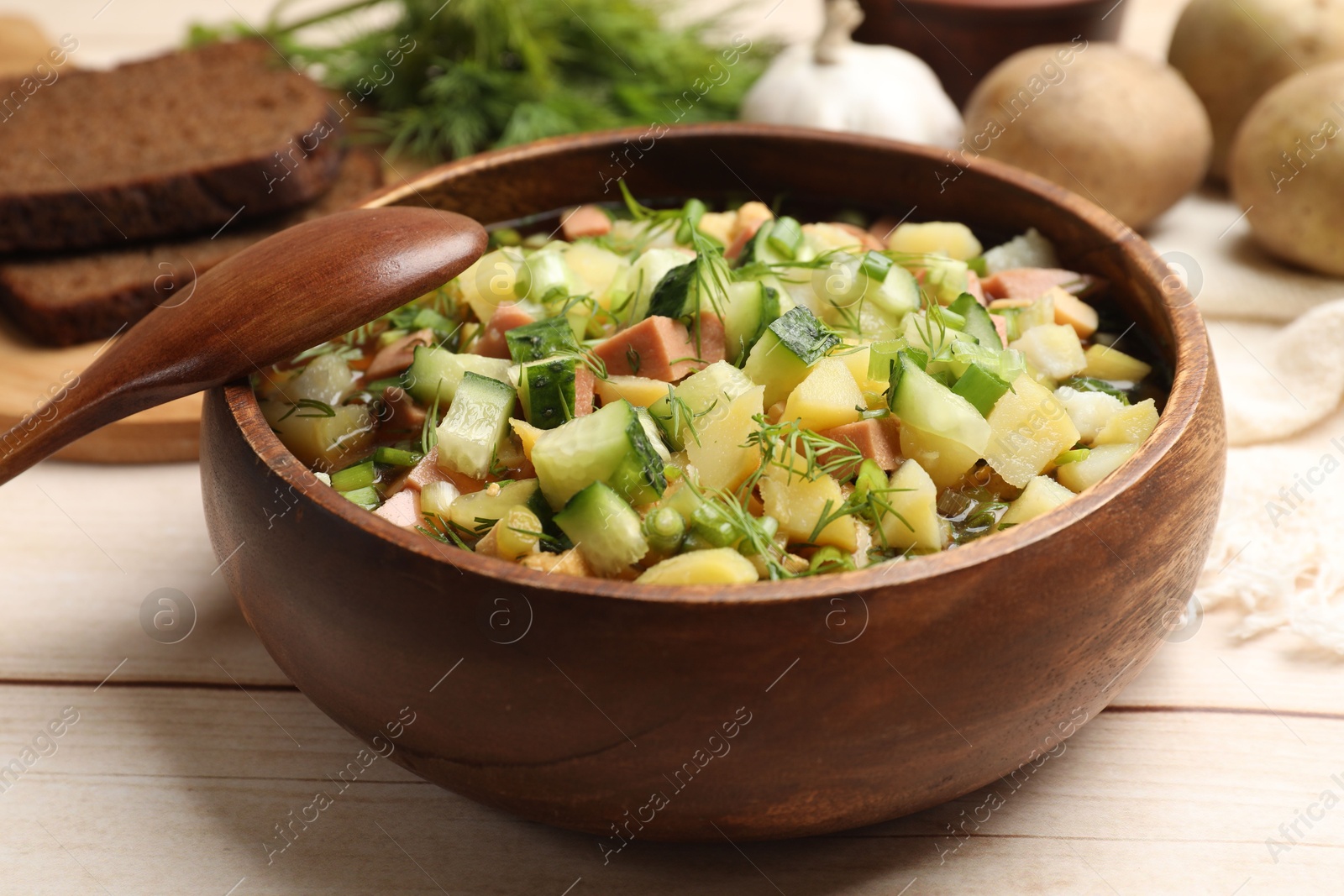 Photo of Delicious okroshka soup with kvass and ingredients on white wooden table, closeup