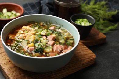 Photo of Delicious okroshka soup with kvass and ingredients on black table, closeup