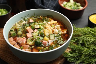 Photo of Delicious okroshka soup with kvass and ingredients on black table, closeup