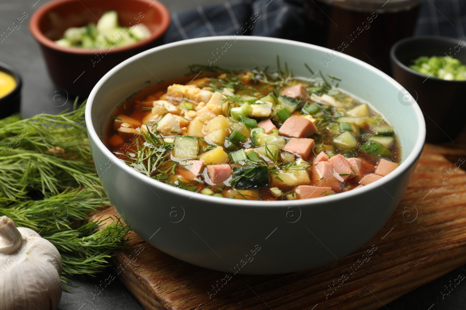 Photo of Delicious okroshka soup with kvass and ingredients on black table, closeup