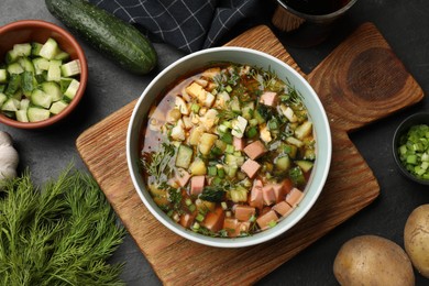 Photo of Delicious okroshka soup with kvass and ingredients on black table, flat lay