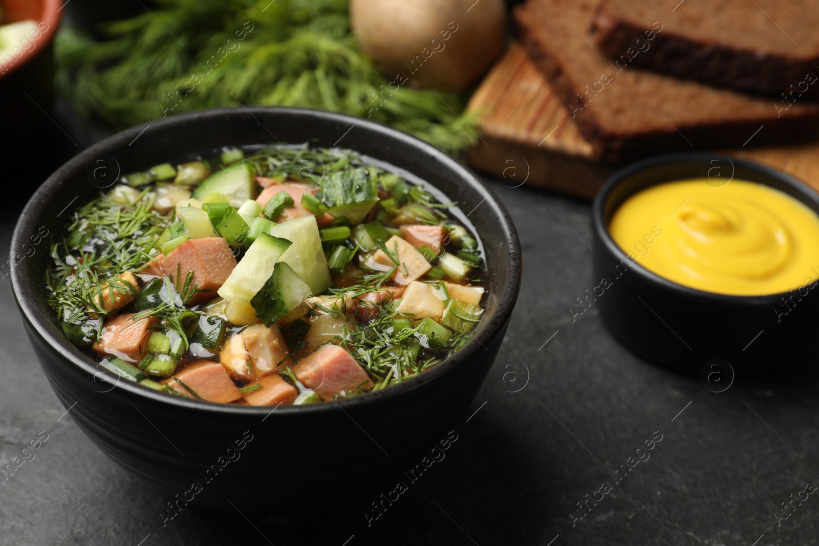 Photo of Delicious okroshka soup with kvass and ingredients on black table, closeup