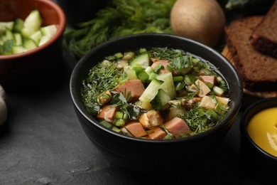 Photo of Delicious okroshka soup with kvass and ingredients on black table, closeup