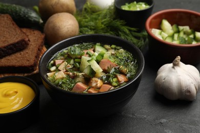 Photo of Delicious okroshka soup with kvass and ingredients on black table, closeup