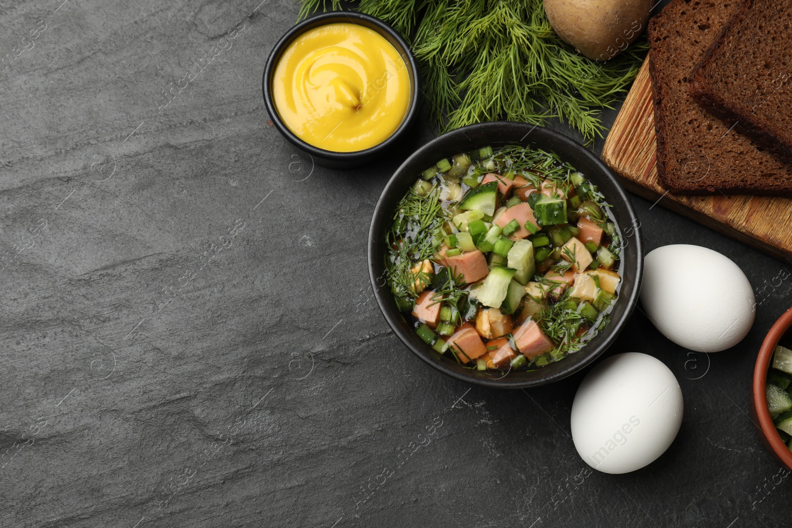 Photo of Delicious okroshka soup with kvass and ingredients on black table, flat lay. Space for text