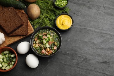 Photo of Delicious okroshka soup with kvass and ingredients on black table, flat lay. Space for text