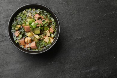 Photo of Delicious okroshka soup with kvass on black table, top view. Space for text