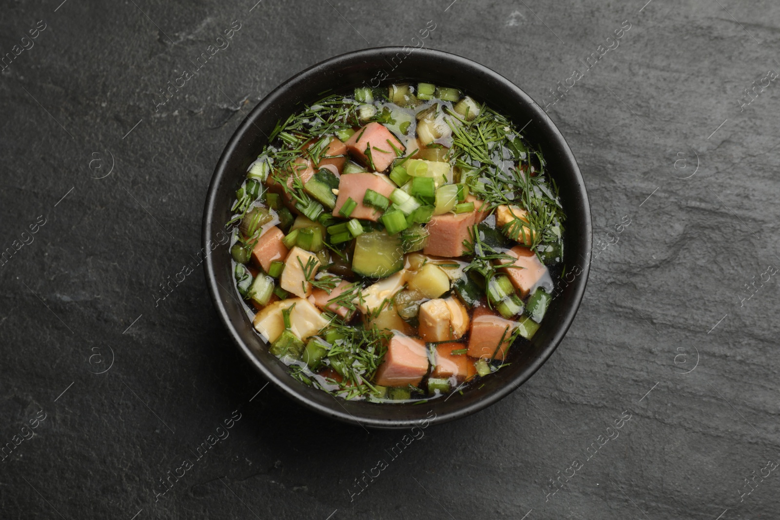 Photo of Delicious okroshka soup with kvass on black table, top view