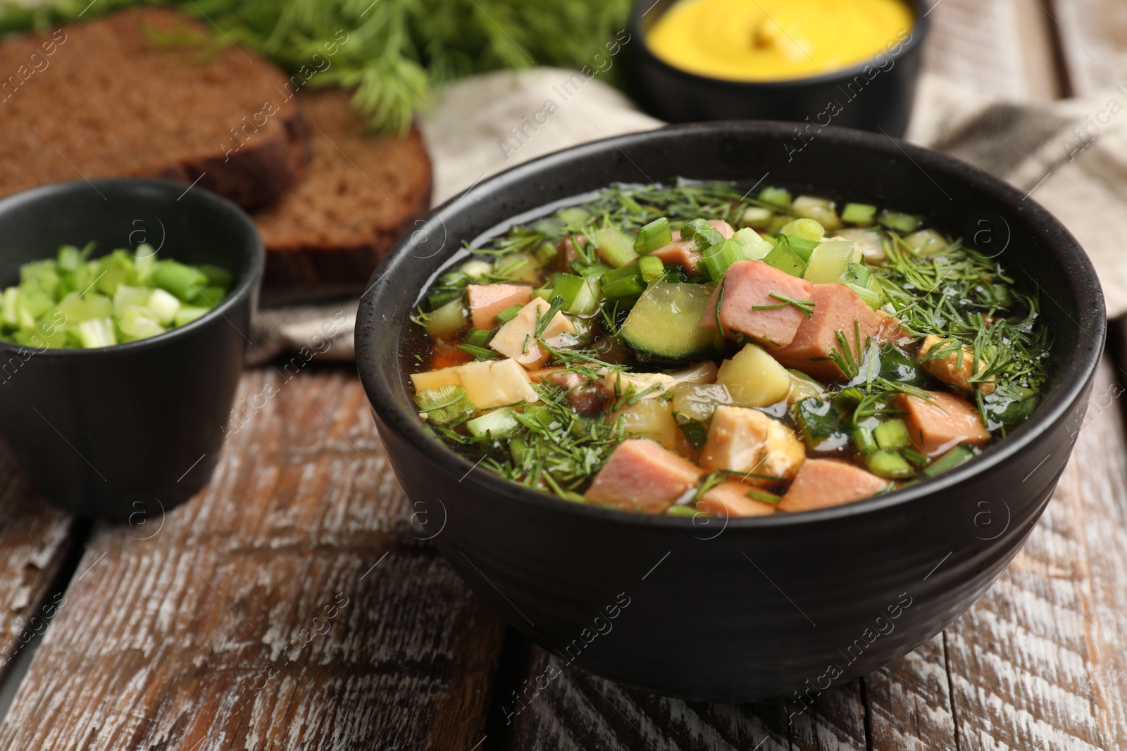 Photo of Delicious okroshka soup with kvass and ingredients on wooden table, closeup