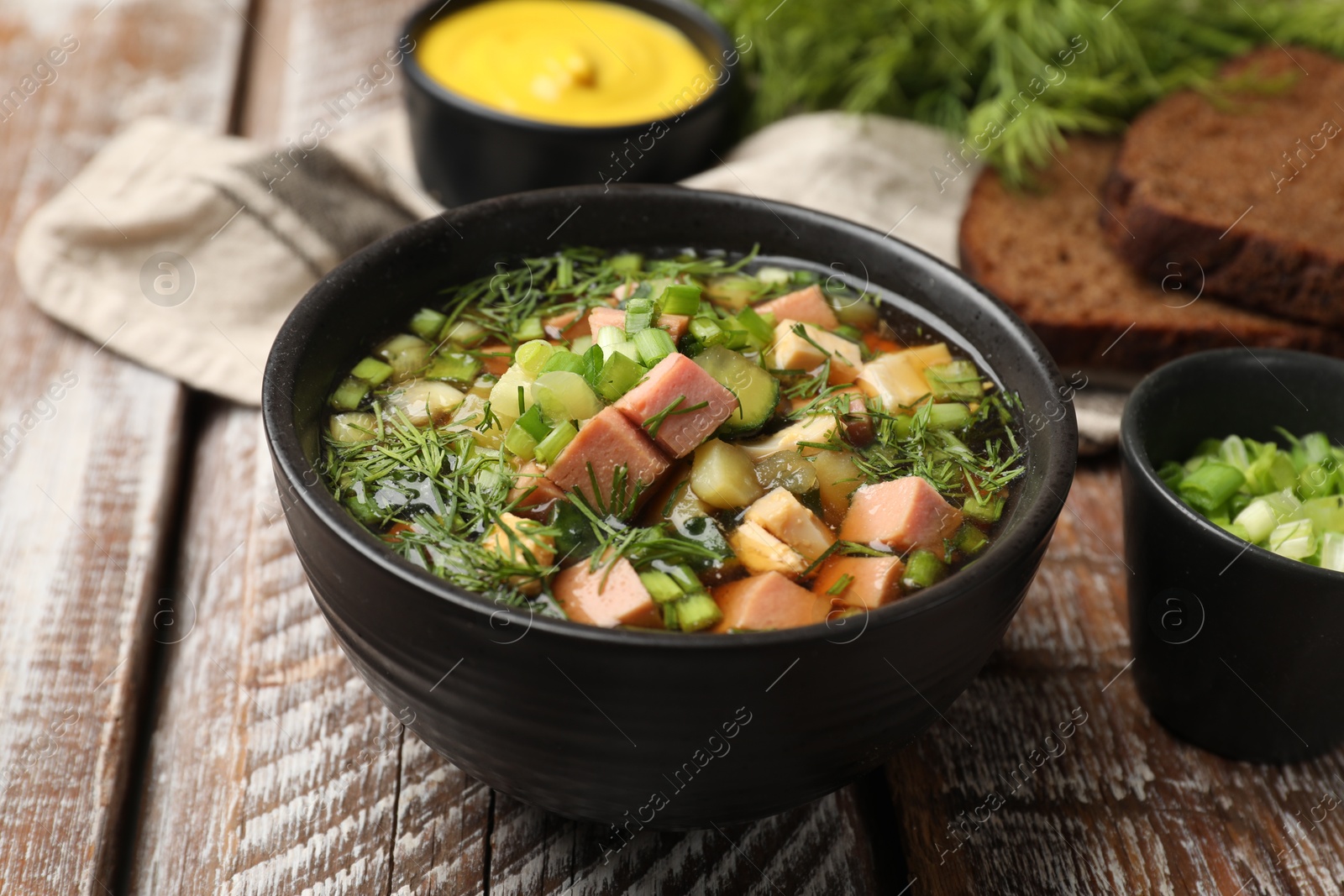 Photo of Delicious okroshka soup with kvass and ingredients on wooden table, closeup