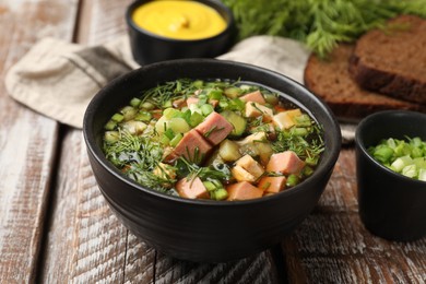 Photo of Delicious okroshka soup with kvass and ingredients on wooden table, closeup