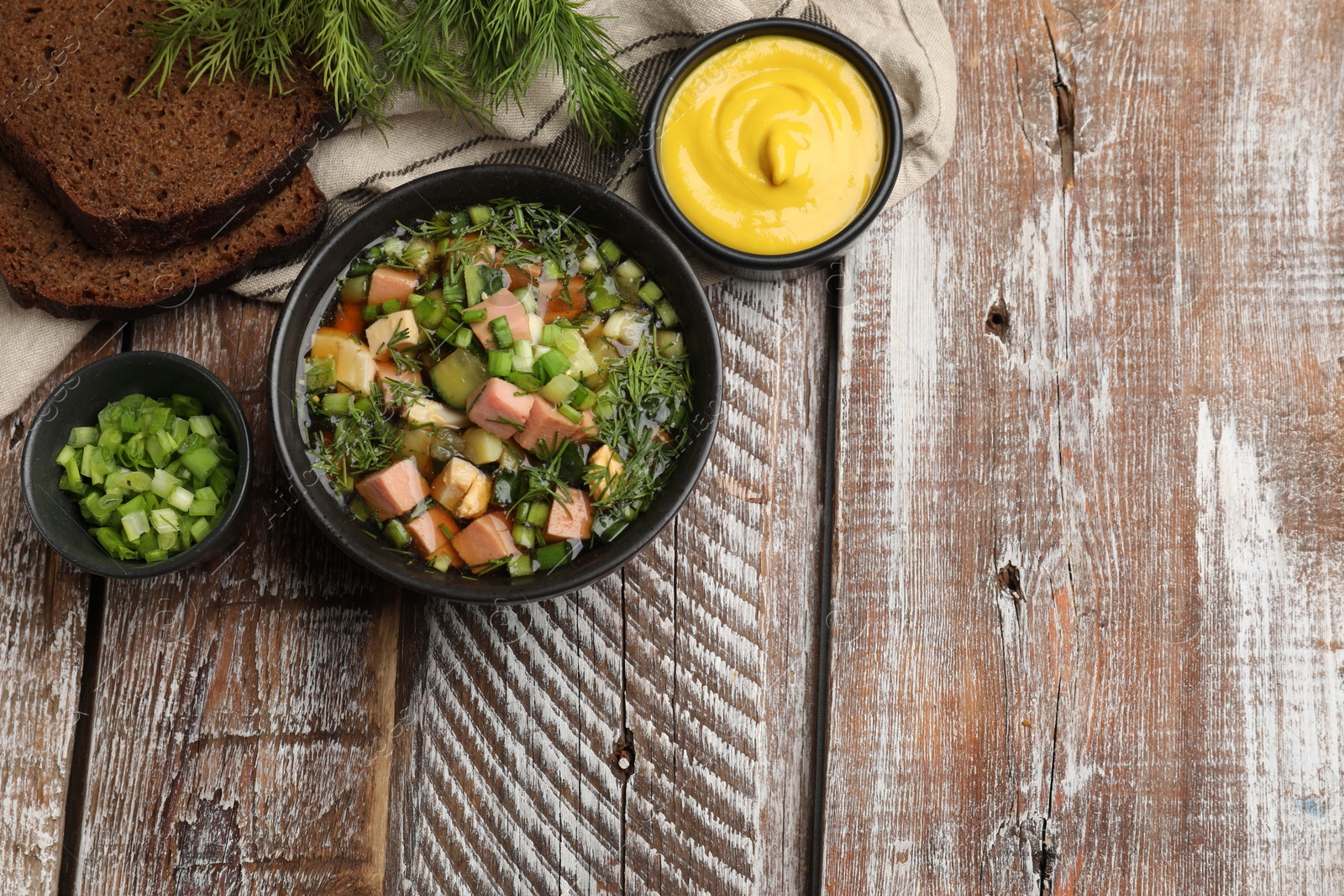 Photo of Delicious okroshka soup with kvass and ingredients on wooden table, flat lay. Space for text