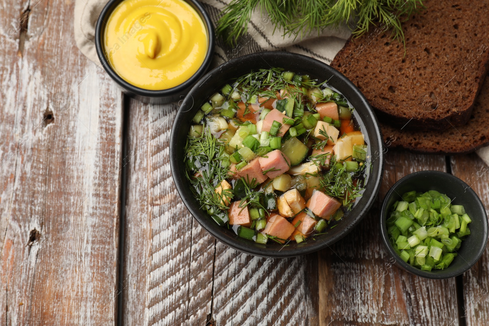 Photo of Delicious okroshka soup with kvass and ingredients on wooden table, flat lay. Space for text