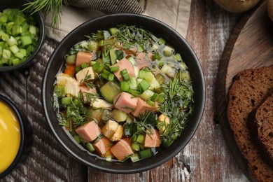 Photo of Delicious okroshka soup with kvass and ingredients on wooden table, flat lay