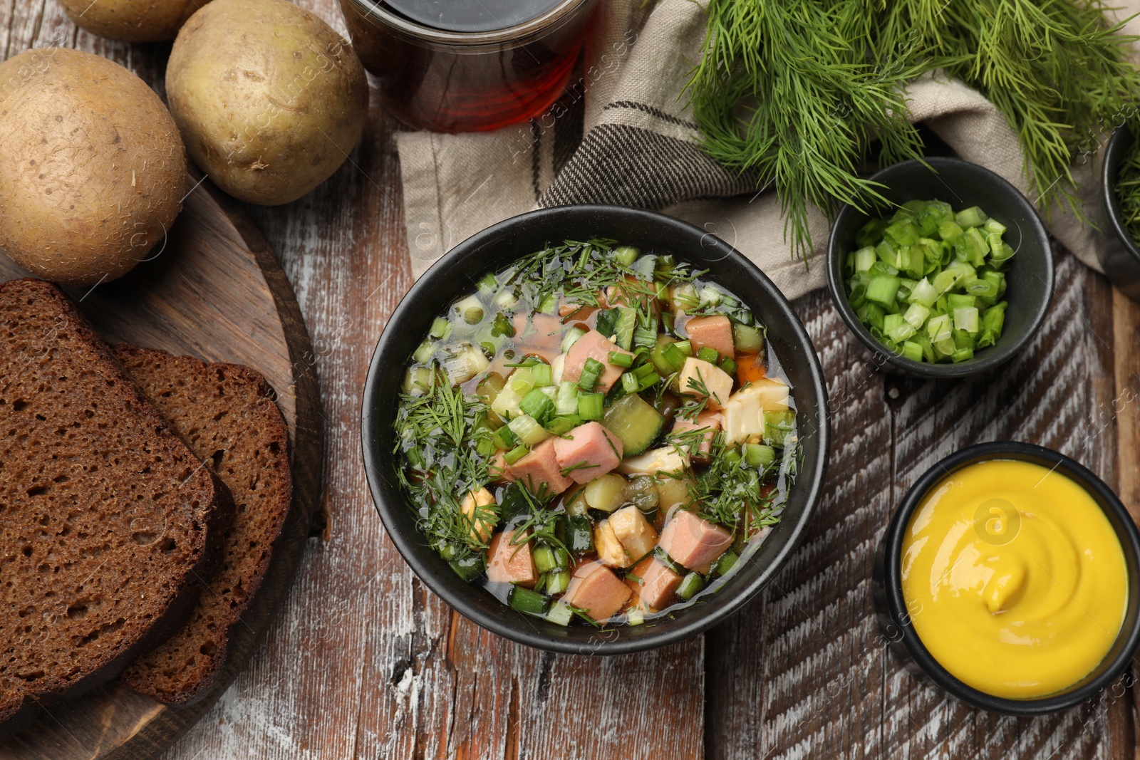 Photo of Delicious okroshka soup with kvass and ingredients on wooden table, flat lay