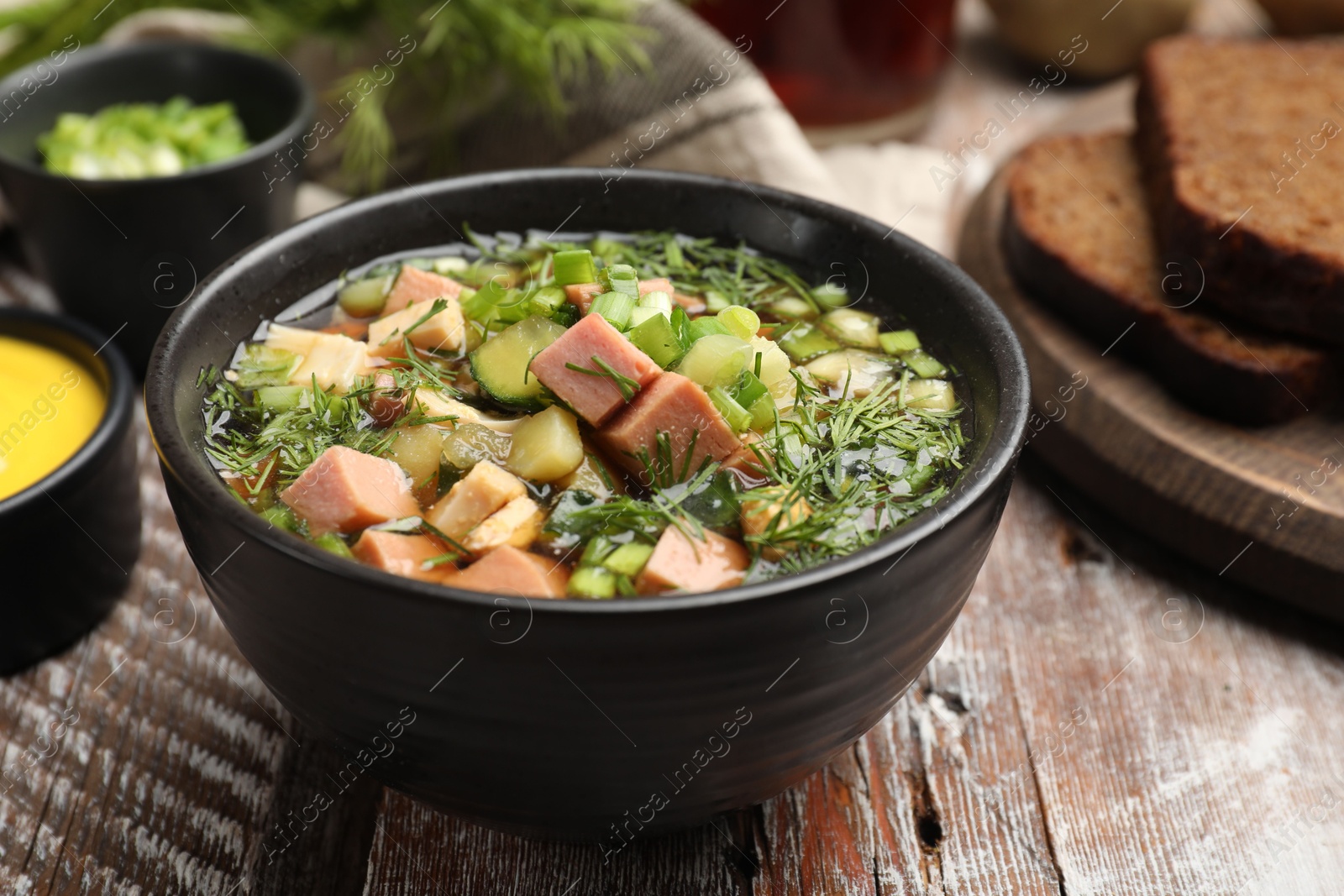 Photo of Delicious okroshka soup with kvass and ingredients on wooden table, closeup