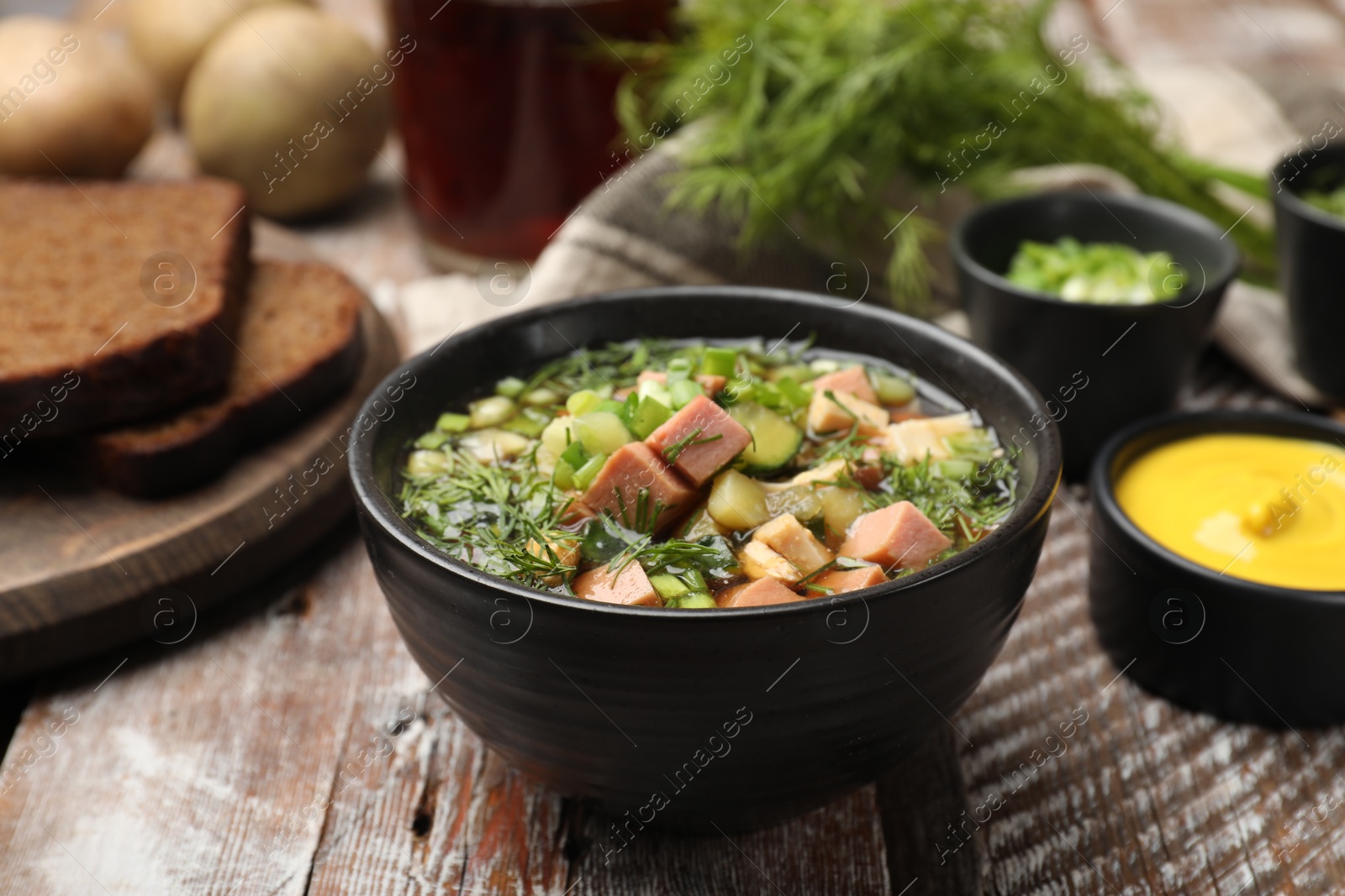 Photo of Delicious okroshka soup with kvass and ingredients on wooden table, closeup