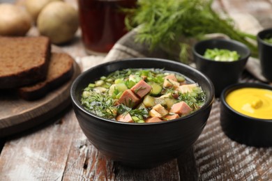 Photo of Delicious okroshka soup with kvass and ingredients on wooden table, closeup