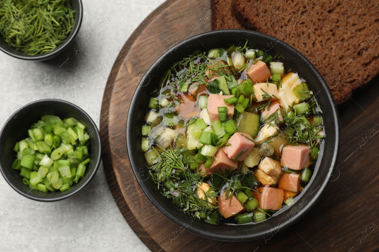 Photo of Delicious okroshka soup with kvass and ingredients on light table, top view