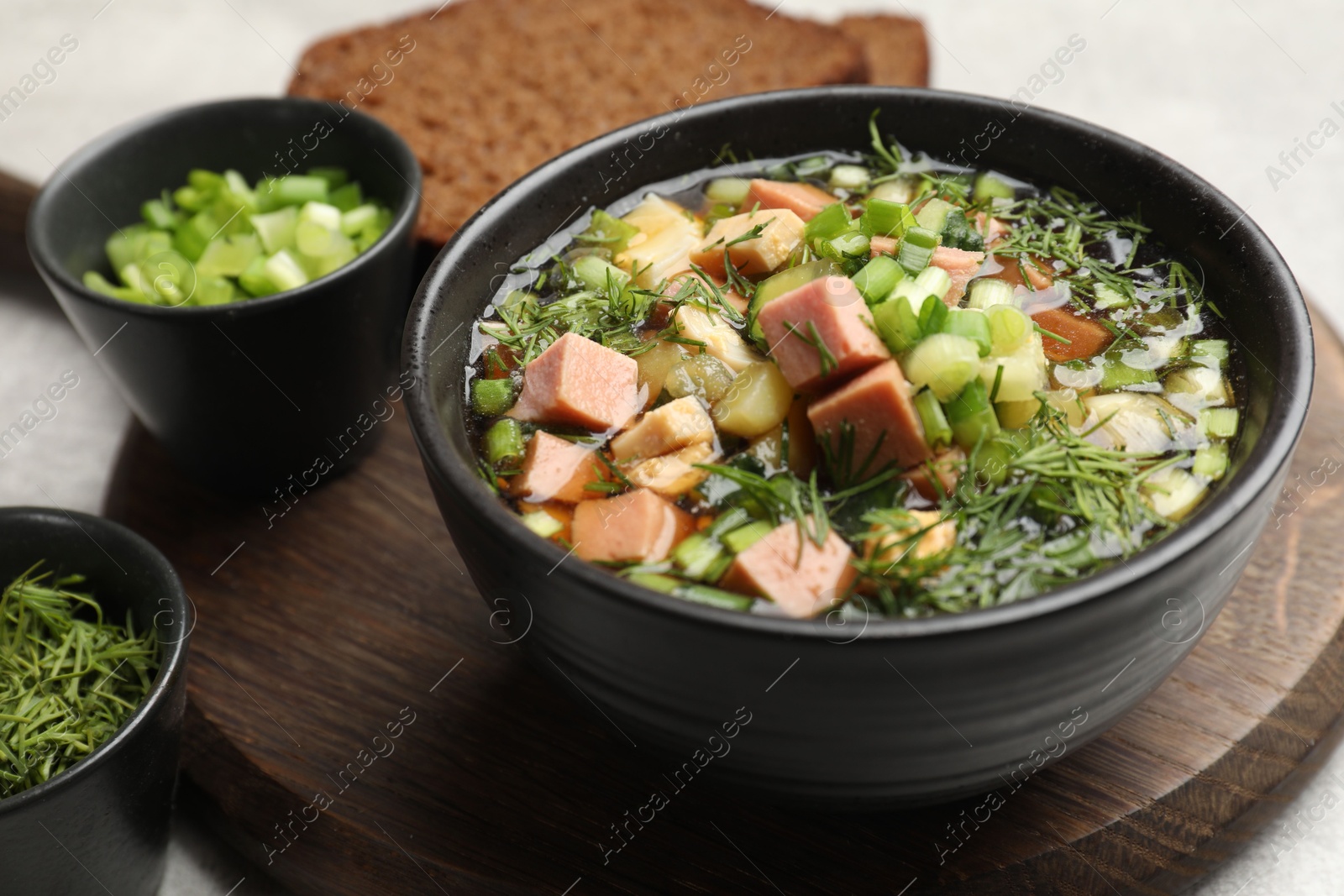 Photo of Delicious okroshka soup with kvass and ingredients on light table, closeup