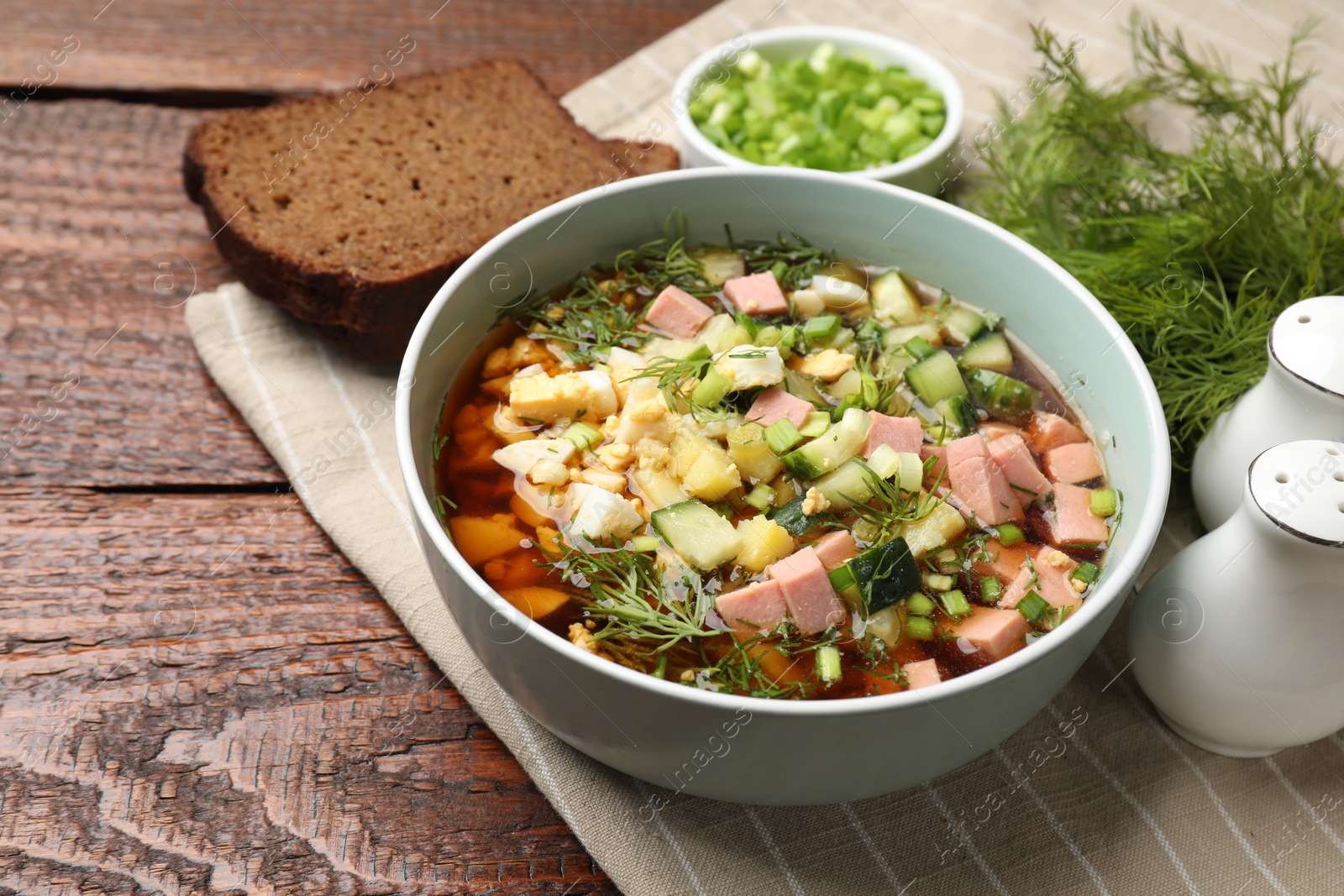 Photo of Delicious okroshka soup with kvass served on wooden table, closeup