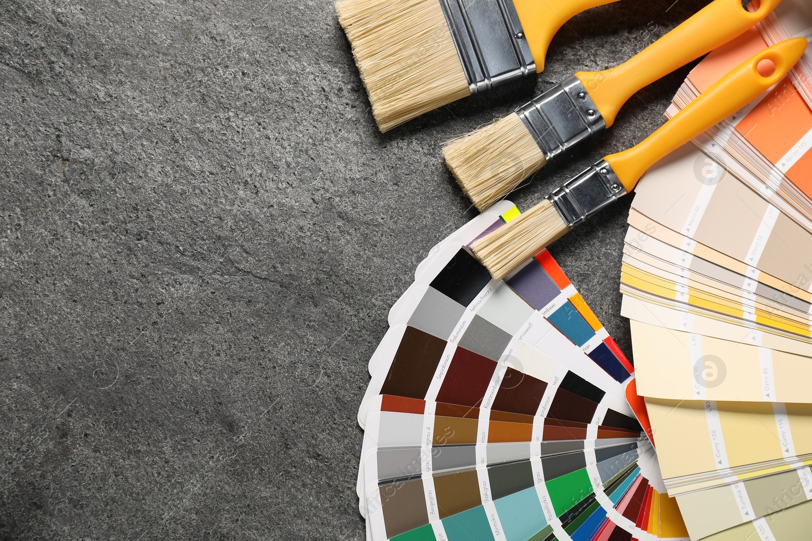 Photo of Color selection chart and paint brushes on grey table, flat lay with space for text. Decorating and design