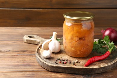 Photo of Canned meat in glass jar and fresh products on wooden table, space for text