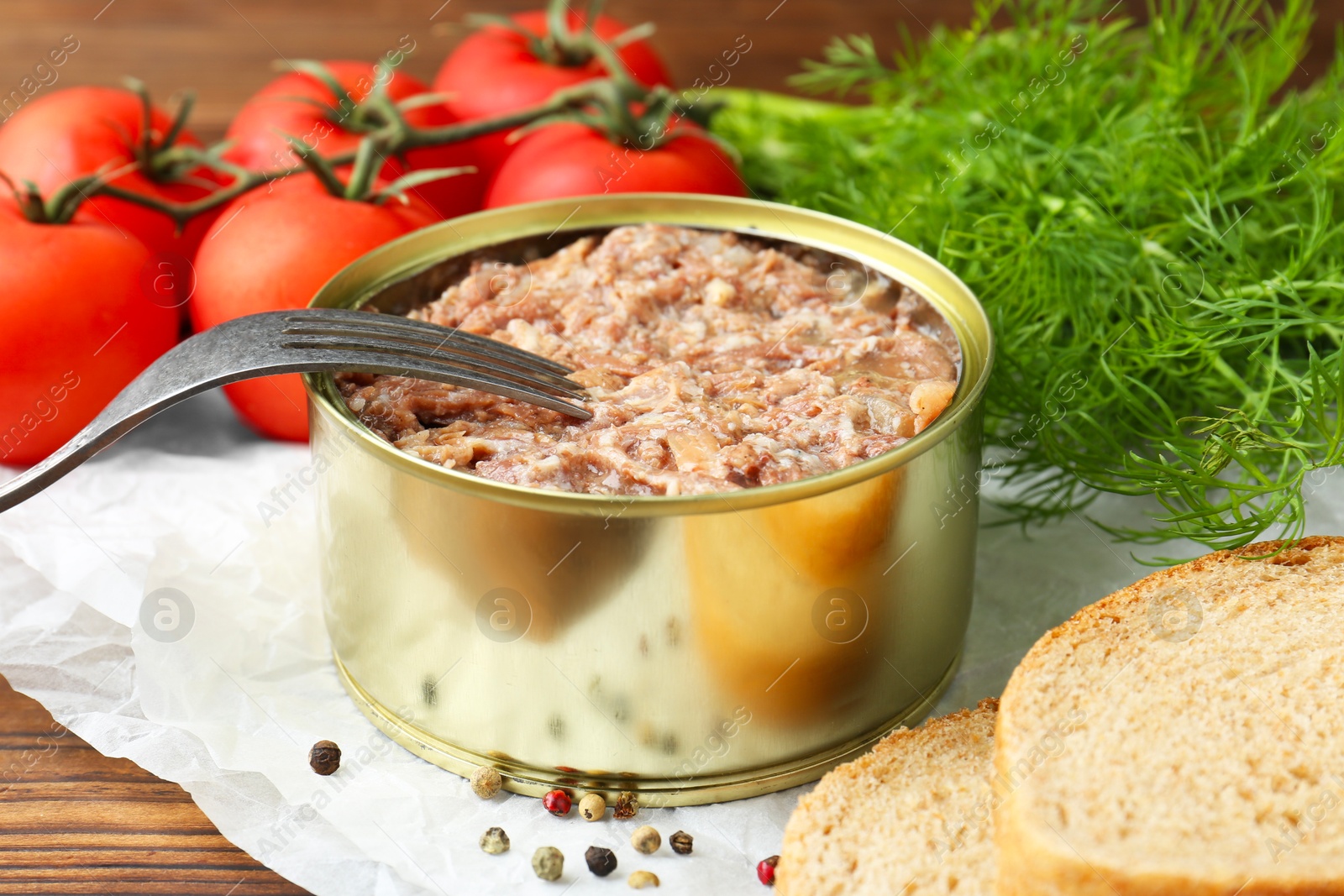 Photo of Canned meat in tin can served on wooden table, closeup