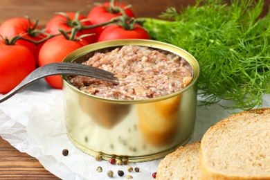 Photo of Canned meat in tin can served on wooden table, closeup