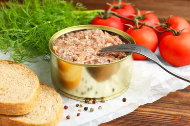 Photo of Canned meat in tin can served on wooden table, closeup