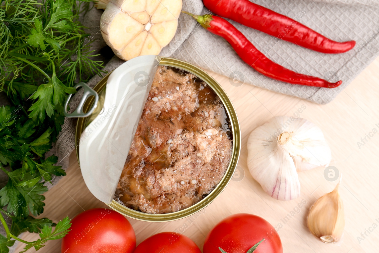 Photo of Canned meat in tin can and other products on wooden table, top view